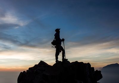Low angle view of silhouette statue on rock against sky during sunrise
