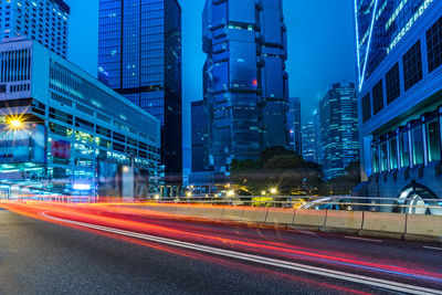 Light trails on road by buildings in city at night