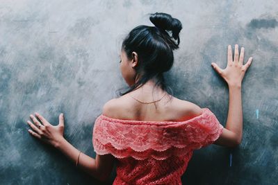 Rear view of woman standing against wall