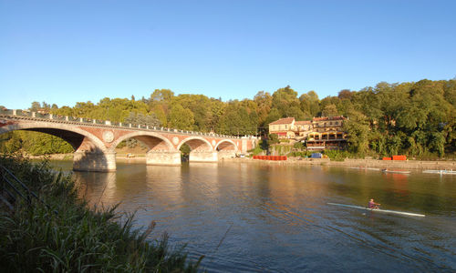 Arch bridge over river against clear sky