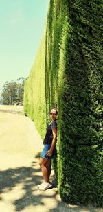 Side view of woman standing by ivy wall