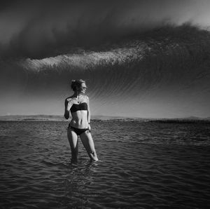 Woman standing in sea against sky