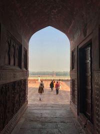 People walking on footpath seen through arch