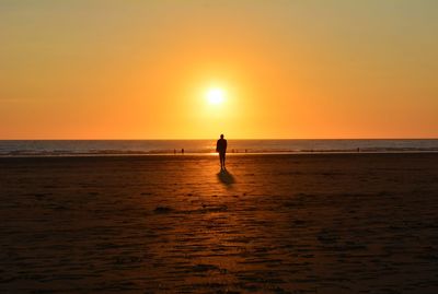 Silhouette people on beach against sky during sunset