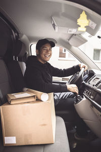 Portrait of happy driver with package sitting in truck