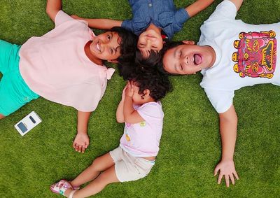 High angle view of happy children lying down on grass
