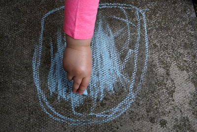 Close-up of girl drawing on concrete