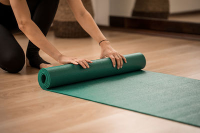 Low section of woman hands unfolding yoga mat