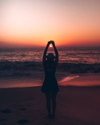 Full length of woman standing at beach during sunset