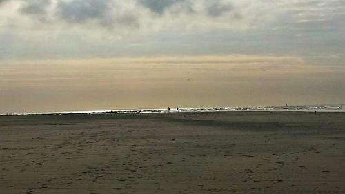 Scenic view of beach against cloudy sky