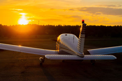 Airplane on runway against sky during sunset