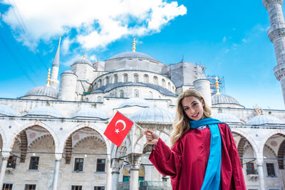 Portrait of smiling young woman against buildings