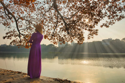 Beauty vietnamese woman wearing ao dai dress at hoan kiem lake in sunset.