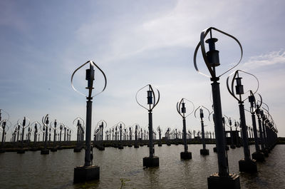 Street lights on bridge over river against sky