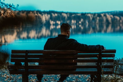 Rear view of man sitting on bench at park