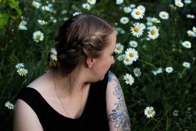 Portrait of young woman sitting in  a field of daisies