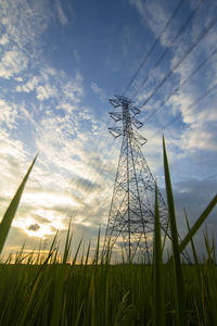 Low angle view of electricity pylon on field against sky