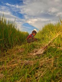 Rear view of child on field against sky