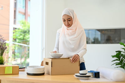 Young businesswoman in hijab packing parcels