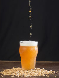 Close-up of beer glass on table against black background