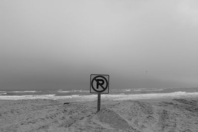 Information sign on beach against sky