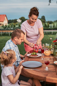 Family having a meal from grill during summer picnic outdoor dinner in a home garden