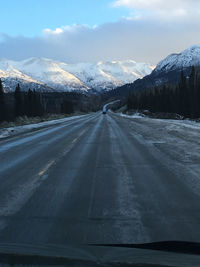 Road amidst snowcapped mountains against sky