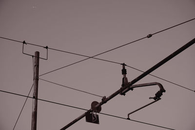 Low angle view of silhouette birds perching on cable against sky