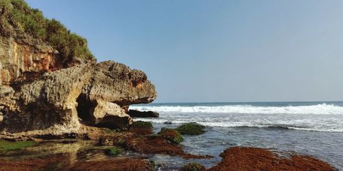 Rock formation on beach against clear sky