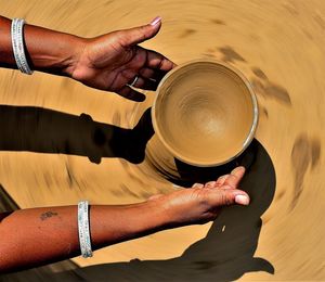 Cropped hands of a woman potter shaping earthenware on a pottery wheel