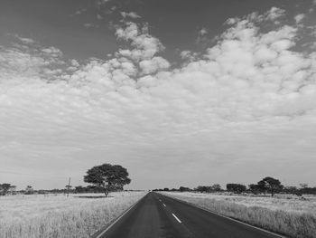 Road amidst field against sky