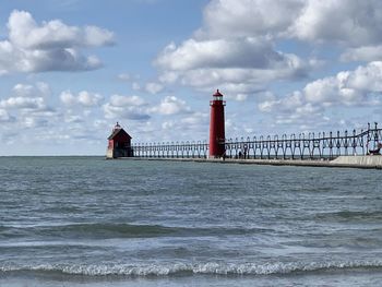 Lighthouse on beach by sea against sky