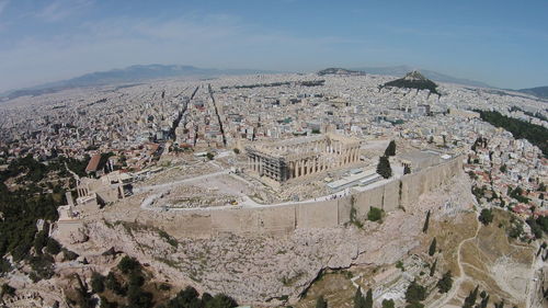 Aerial view of parthenon on acropolis hill by residential district against sky