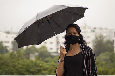 Portrait of man holding umbrella standing during rainy season