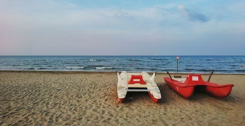 Deck chairs on beach against sky