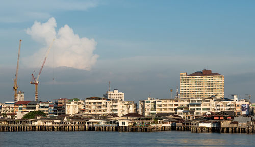 View of cityscape by sea against sky