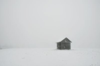 House on snow covered field against sky