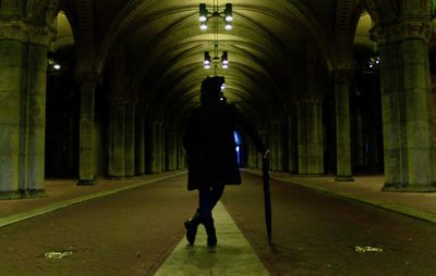 Rear view of man walking in illuminated building