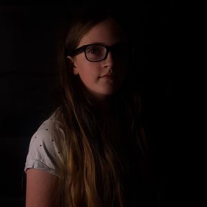 Close-up portrait of girl against black background