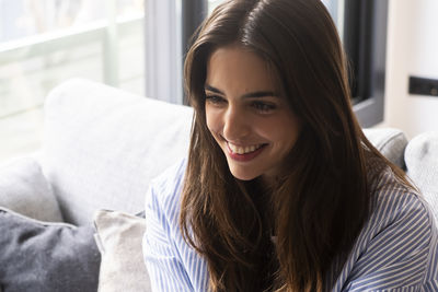 Portrait of young woman sitting on bed at home