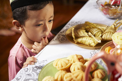 Boy standing beside table with food in plates