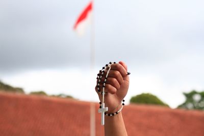 Close-up of hand holding prayer beads against flag