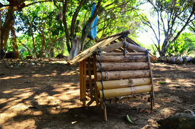 Wooden structure on field against trees in forest