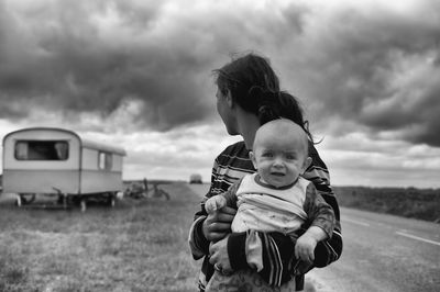 Portrait of father and son on field against sky