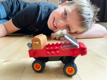 Portrait of cute boy with toy car on floor at home