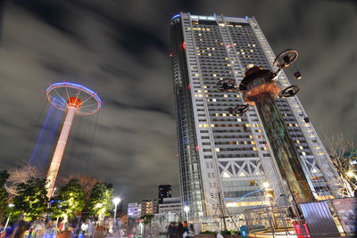 Illuminated ferris wheel in city against sky