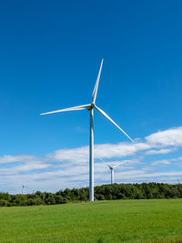 Wind turbines in field against blue sky