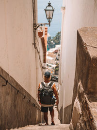 Rear view of woman walking on alley amidst buildings