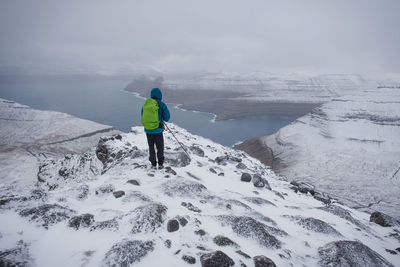 Rear view of person on snowcapped mountain against sky