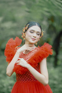 Portrait of young woman standing against trees